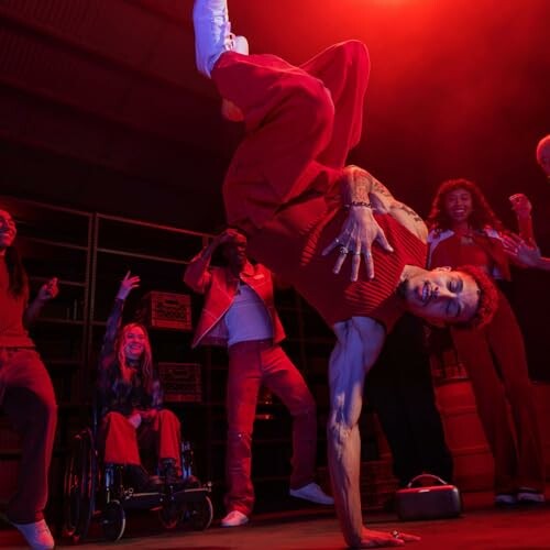 Breakdancer performing in red-lit room with onlookers